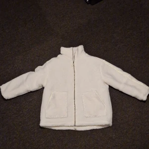 Vit teddyjacka - Mysig vit teddyjacka i mycket bra skick. Perfekt för kyliga höst- och vinterdagar. Jackan har en dragkedja framtill och två stora fickor. Den är långärmad och har en normal passform. Supergosig och trendig!