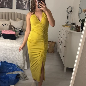 Gul långklänning med slits - Säljer en snygg gul långklänning med en djup v-ringning och slits framtill. Klänningen har en tight passform och är perfekt för sommarens fester. Materialet är mjukt och stretchigt, vilket gör den bekväm att bära hela dagen. Perfekt för att sticka ut på festen! 🌟