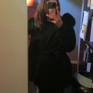 Svart kappa med päls luva  - Svart kappa med äkta päls luva, Passar XS-M i storleken. Den går lite längre under rumpan.