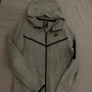 Grå Nike tech fleece hoodie - Helt ny Grå Nike tech fleece hoodie i storlek S, skick 10/10, nypris 1500kr! Perfekt och stilren till både träningssammanhang och till vardags. 👍