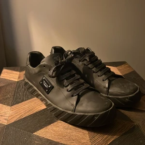 Svarta sneakers från Philipp Plein - Snygga svarta sneakers i skinn från Philipp Plein med cool dödskalle-detalj på hälen. Använt en del för ett bra tag sen, så ser inte direkt sprillans ny ut men ser fortfarande bra ut. OBS: ena dödskallen på baksidan av hälen fattar ett ben. Annars inga konstigheter med dem!