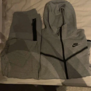 Grå hoodie från Nike - Säljer en grå hoodie från Nike i mycket bra skick. Den har en dragkedja framtill och en klassisk Nike-logga på bröstet. Perfekt för träning eller en chill dag hemma. Superbekväm och stilren design!