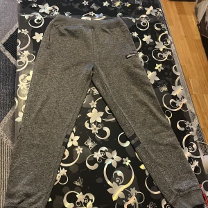 Grå mjukisbyxor från Ellesse - Säljer ett par grå mjukisbyxor från Ellesse i bra skick. De har en normal passform och är perfekta för avslappnade dagar. Superbekväma och stilrena!