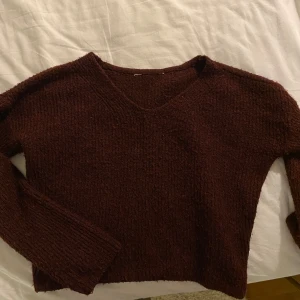 Vinröd stickad tröja - Säljer en mysig vinröd stickad tröja med v-ringning. Perfekt för höst och vinter! Tröjan har långa ärmar och en skön passform. Den är i bra skick och passar perfekt för en avslappnad stil. Hör av dig vid intresse!