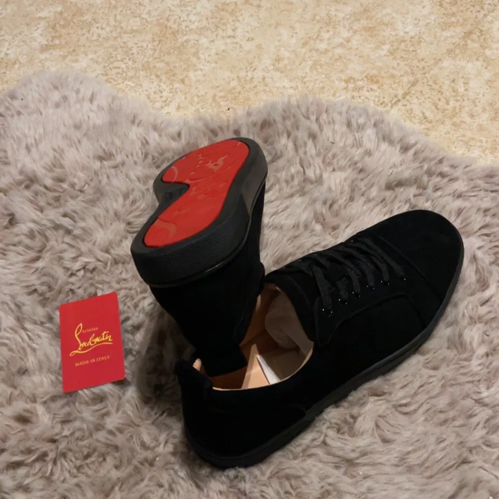 Säljer ett par snygga svarta sneakers från Christian Louboutin i mocka. De har den ikoniska röda sulan och klassisk snörning. Perfekta för både vardag och fest!. Skor.