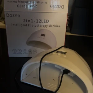 Lampa för naglar  - Dazzle 2in1-12LED Intelligent Phototherapy Machine är en vit LED-lampa för nagelvård. Den har en bågformad design med plats för händer eller fötter och är utrustad med 12 LED-lampor för effektiv härdning av nagellack. Perfekt för hemmabruk manikyr och pedikyr😊🩷