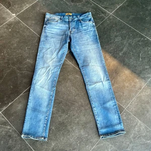 Jack & Jones jeans  - Säljer ett par klassiska blå jeansbyxor i bra skick. De har en slim passformen och är perfekta för vardagsbruk. Byxorna har en traditionell femficksdesign och en snygg tvätt som ger en avslappnad look. Perfekta för både höst och vår! Helt nya, endast provade. Mvh vestimenta😊