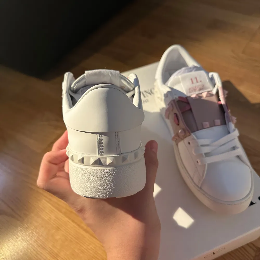 Säljer ett par snygga Valentino Rockstud sneakers i vitt läder med rosa detaljer. Skorna har de ikoniska nitarna och en stilren design. Perfekta för att ge din outfit en lyxig touch. De är i nytt skick och kommer med originalförpackning. Priset går att förändras. Skor.