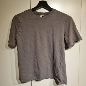 Grå t-shirt - Säljer en enkel och stilren grå t-shirt i bomull. Perfekt för vardagsbruk med en normal passform och korta ärmar. Passar till alla tillfällen och är ett måste i garderoben!