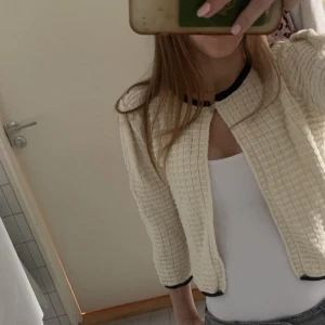 Beige quiltad kofta - Säljer en superfin beige quiltad kofta med trekvartsärm. Den har en stilren design med svarta detaljer vid ärmslut och krage. Perfekt för höst och vinter💕💕Passar både till vardags och fest!