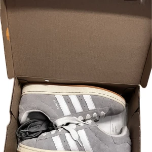 Grå Adidas Campus unisex storlek 44 - Säljer ett par grå unisex Adidas Campus, storlek 44.  De är i riktigt fint skick, endast använda någon enstaka gång (testade). Så skicket är 9,5-10/10, sprillans nya. De är givetvis äkta, jag har  äkthetsbevis. Föreslå ett pris du är villig att betala och det är bara att fråga ifall du undrar något eller vill ha mer bilder. 