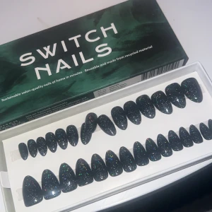 Svarta glittriga lösnaglar från Switch Nails - Snygga svarta lösnaglar med glittereffekt från Switch Nails. Perfekta för en glamorös look och enkla att applicera hemma. Återanvändbara och tillverkade av återvunnet material. Få salongskvalitet på några minuter!