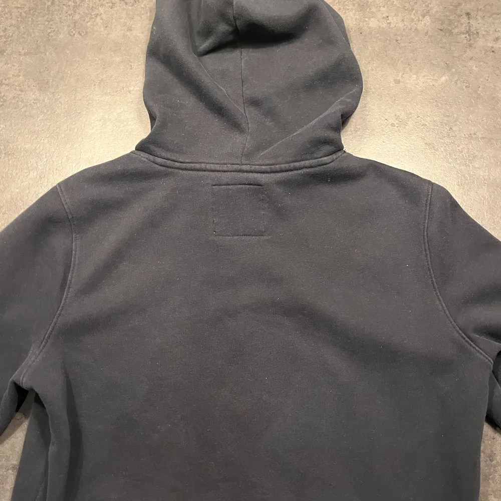 Säljer en snygg och bekväm mörkblå hoodie från Hollister. Den har en klassisk design med en liten logga på bröstet och justerbara snören i huvan. Perfekt för en avslappnad stil och passar till de flesta tillfällen. Den är i bra skick och redo för en ny ägare!. Tröjor & Koftor.