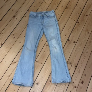 Ljusblå bootcut jeans - Säljer ett par ljusblå bootcut jeans med klassisk design. De har en lågmidjad passform och är perfekta för en avslappnad stil. Jeansen har en liten fläck på framsidan