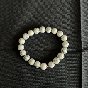 Vitt armband med marmorerade pärlor - Snyggt elastiskt armband med vita marmorerade pärlor. Perfekt accessoar för att ge en stilren touch till din outfit. Passar bra till både vardag och speciella tillfällen. Skicka gärna pris förslag