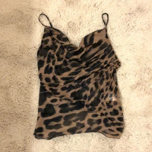 Leopardmönstrad linne - Snygg leopardmönstrad linne med tunna axelband och draperad framsida. Lite genomskinlig men annars jättefin. 