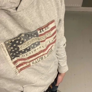 Ralph lauren hoodie - En unik hoodie i grå färg från ralph lauren med snyggt tryck. Har en liten defekt vid fickan som du ser på sista bilden. 