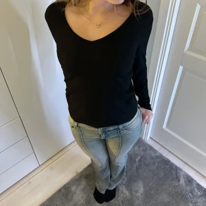 Svart långärmad tröja - Säljer en stilren svart ribbad tröja från Gina Tricot. Tröjan har en v-ringad hals och långa ärmar, perfekt för en enkel och snygg look. Passar bra till både jeans och kjol. 🖤