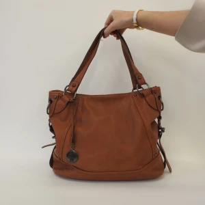 Brun axelväska  - Snygg brun axelväska med dekorativa detaljer och en praktisk dragkedja. Perfekt för att bära med sig det nödvändigaste. Väskan har en stilren design och passar till många olika tillfällen.💜