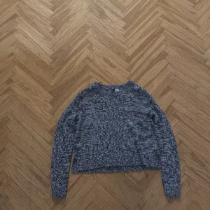 Gråmelerad stickad tröja - Säljer en mysig gråmelerad stickad tröja med långa ärmar. Perfekt för kyligare dagar och enkel att matcha med olika outfits. Tröjan har en klassisk rund halsringning.