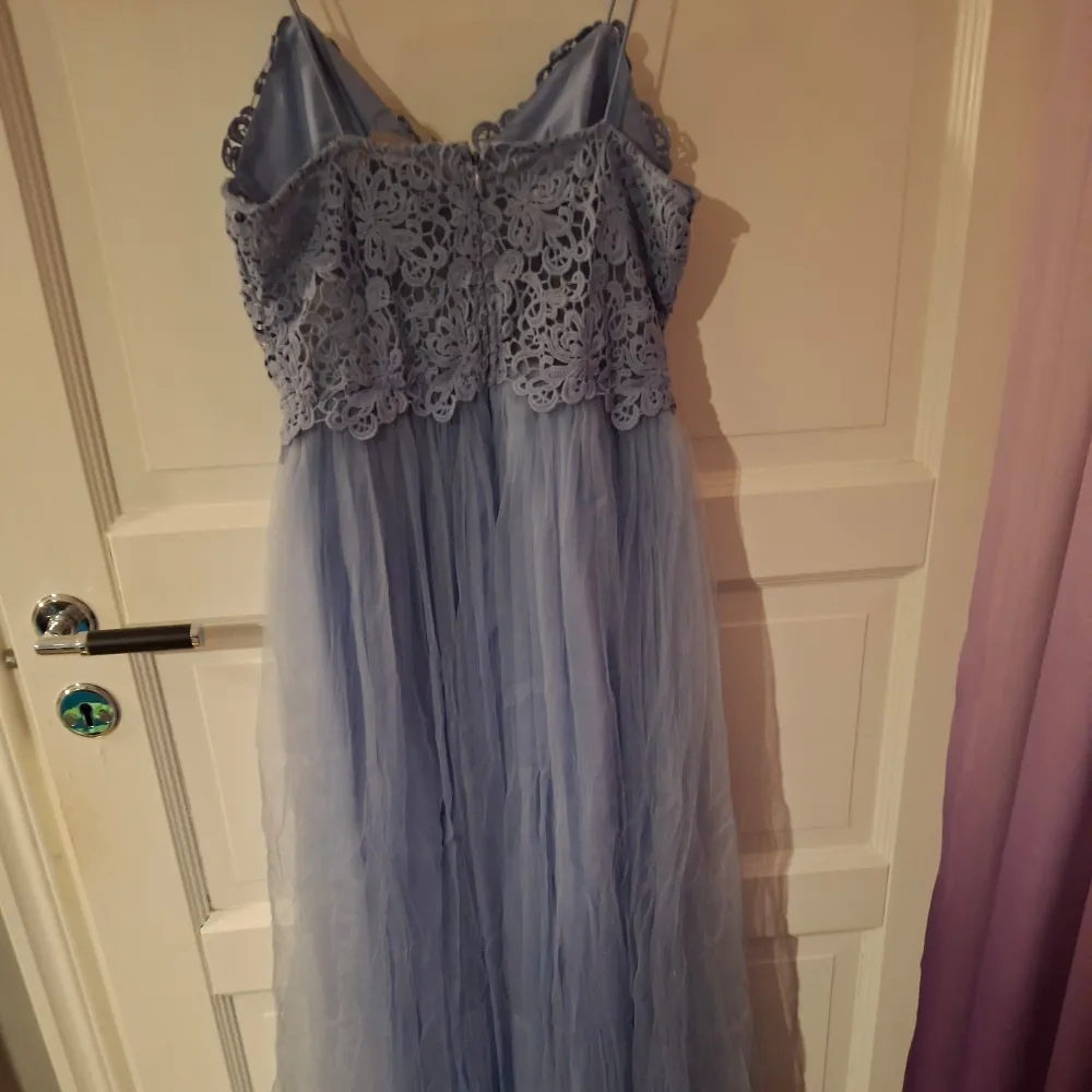 Säljer en vacker ljusblå långklänning från ASOS med spetsdetaljer på överdelen och en luftig kjol. Klänningen har smala axelband och en elegant design som passar perfekt för speciella tillfällen. Perfekt för dig som vill känna dig extra fin!. Mekot.