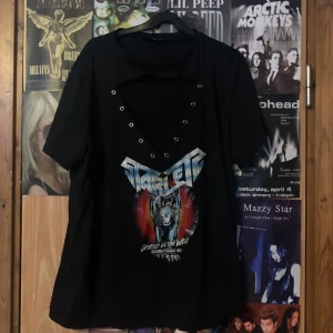 Svart t-shirt med tryck, saknar band men går att fixa. - Cool svart t-shirt med ett tryck av en tiger. Den har en unik v-ringad design, saknar ett band till alla små nitar, men går att fixa hemma. Perfekt för en rockig stil!