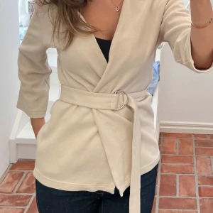 Beige kofta från Selected Femme - Beige finstickad kofta från Selected Femme med trekvartsärm och ett band i midjan. I jättefint skick och bara använd några få gånger❣️