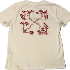 Vit t-shirt från Off-White - Äkta💲Säljer  vit t-shirt från Off-White med ett snyggt rött broderi på baksidan. Perfekt för dig som vill ha något unikt och stilrent i garderoben.