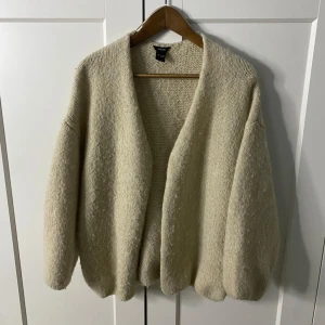Beige stickad kofta  - Mysig beige stickad kofta från H&M med en öppen design. Perfekt för kyliga dagar med sin mjuka och bekväma passform. Koftan har långa ärmar och en enkel stil som passar till det mesta. Ganska populär just nu!