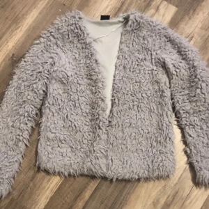 Grå teddyjacka från Gina Tricot - Supermysig grå teddyjacka från Gina Tricot i storlek XS. Perfekt för kyliga dagar när du vill vara både varm och stilren. Jackan har en fluffig textur och långa ärmar, vilket gör den idealisk för höst och vinter. Ett måste för garderoben! 🐻