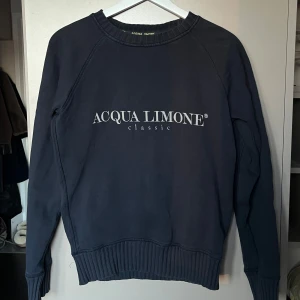 Mörkblå tröja från Acqua Limone - Säljer en mörkblå tröja från Acqua Limone i mycket bra skick. Den har ett stort tryck med märkesnamnet på framsidan och en cool gul citronlogga på baksidan. Tröjan är långärmad och har ribbade muddar vid ärmslut och nederkant. Perfekt för både vardag och chill. Storlek XXS men passar även XS. Samt S om du vill ha den lite mindre.
