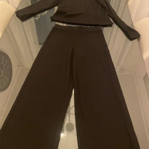 Svart set från Kappahl - Säljer ett svart set från Kappahl i storlek 158. Setet består av en långärmad tröja och byxor i ett mjukt och bekvämt material. Perfekt för en avslappnad dag hemma eller som ett mysigt vardagsplagg. Både tröjan och byxorna har en enkel och stilren design. passar de som har S/M