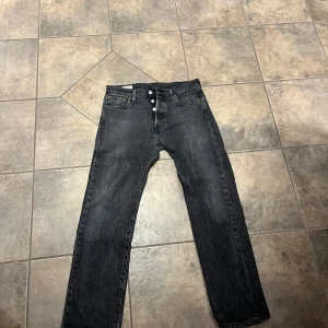 Svarta Levis 501 jeans - Säljer ett par klassiska svarta Levis 501 jeans i bra skick. De har en straight passform och är tillverkade i slitstarkt denim. Perfekta för både vardag och fest. Knappgylf och femficksdesign ger en tidlös look. Passar till allt från t-shirts till skjortor!