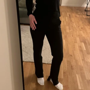 Svarta byxor från NA-KD Reborn - Säljer ett par stilrena svarta byxor från NA-KD Reborn i storlek 36. Byxorna har en normal passform och är perfekta för både vardag och fest och har en slits nere vid foten. De är tillverkade i ett mjukt och bekvämt material som ger en snygg siluett. Perfekta att matcha med en enkel topp eller en dressad blus.💓💓