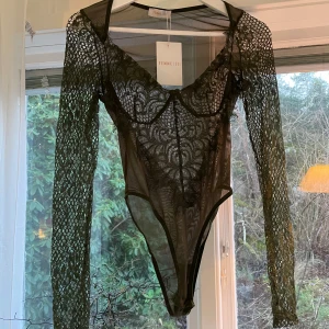 Oanvänd mörkgrön spetsbody  - Oanvänd mörkgrön spetsbody i storlek XS/S. Prislappen är kvar. Långa armar och supersnygg urringning. Från Femme Luxe