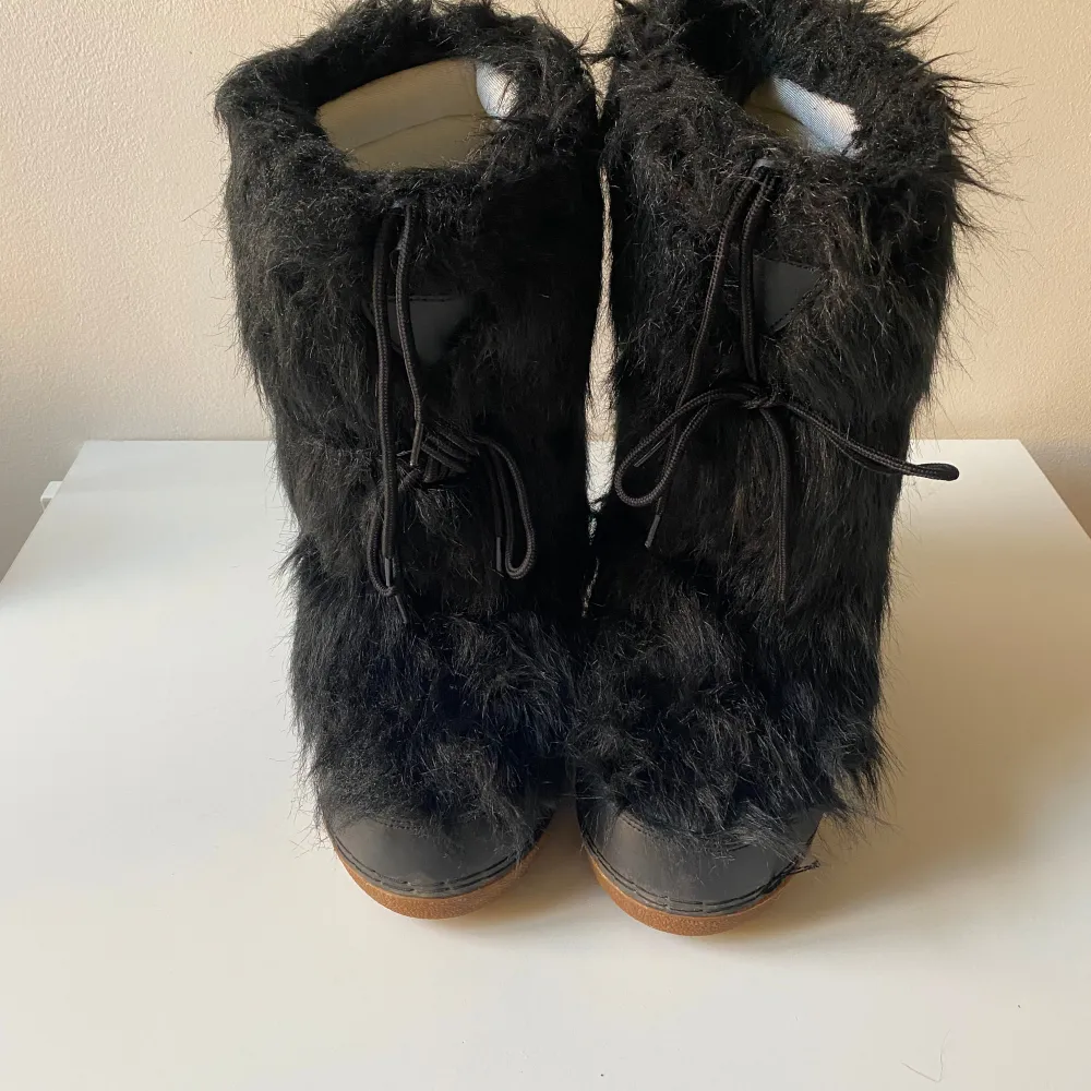 Säljer ett par unika svarta boots från Frenzy i storlek41- 42. De är täckta med fluffig päls och har en robust sula för bra grepp. Perfekta för vinterns kalla dagar. Skorna har snörning framtill för en säker passform.. Skor.