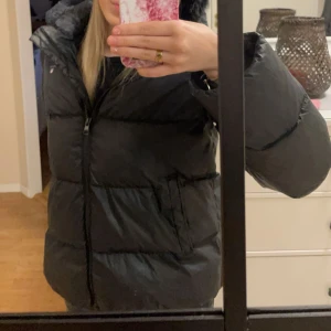 Svart dunjacka med huva - Säljer en svart dunjacka i från gant mycket bra skick. Jackan är köpt på kidsbrandstore. Supervarm och skön att ha på sig! Köpt för ca 4000
