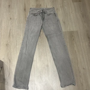 Grå jeansbyxor - Säljer ett par grå jeansbyxor i bra skick. De har en klassisk straight passform och är perfekta för vardagsbruk. Byxorna har en normal midja och är tillverkade i ett slitstarkt denimtyg. Perfekta för både höst och vår!