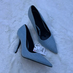 Blå pumps med spetsig tå - Snygga blå pumps i jeansmaterial med spetsig tå och hög klack. Perfekta för en utekväll eller fest! De är helt nya och har fortfarande prislappen kvar. Enkla att matcha med både klänning och jeans för en chic look.