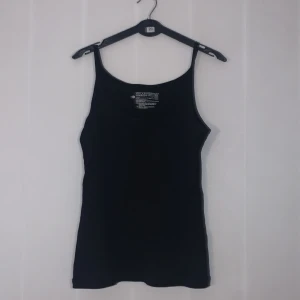 Svart linnetopp från Esmara - Säljer en stilren svart linnetopp från Esmara i storlek M. Perfekt för sommardagar eller som ett basplagg i garderoben. Toppen har smala axelband och är tillverkad i ett mjukt och bekvämt material. Passar både till vardags och festliga tillfällen.