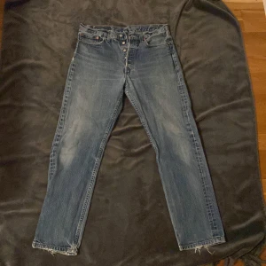 Levis jeans - Säljer ett par klassiska Levis jeans i blå denim. De har en straight passform och är i bra skick med en vintage look. 