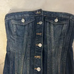 Snygg jeanstopp från Zara i storlek XS. Toppen har en knappförsedd framsida och baksida. Den är gjord av klassiskt blått denimtyg och har en elastisk rygg för extra komfort. Perfekt för en avslappnad sommarlook eller en dag på stan!