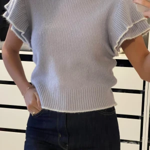 Ljuslila stickad topp från Violet Romance - Säljer en ljuslila stickad topp från Violet Romance. Toppen har korta ärmar med volangdetaljer och en ribbad struktur. Perfekt för en stilren look. Passar bra till jeans eller kjol. 💜