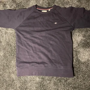 Mörkblå tröja från GANT - Säljer en stilren mörkblå tröja från GANT. En liten logga på bröstet. Perfekt för en avslappnad och snygg look. Passar bra till både jeans och chinos.