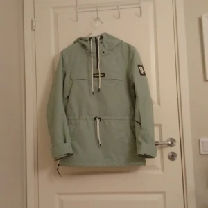 Grön skid/snowboard jacka från Strobe - Snygg grön skidjacka från Strobe med justerbar huva och dragsko i midjan. Jackan har en stor ficka framtill. Den här blivit använd 1 gång och är i bra skick. Vi köpte den för 1000 kr och ny pris 1100