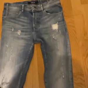 Blåa jeans från Replay - Snygga blå jeans från Replay med slitna detaljer och en cool, avslappnad look. Perfekta för en casual stil. De har en klassisk femficksdesign och en bekväm passform.