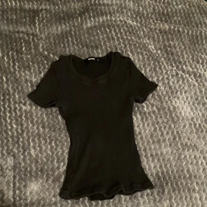 Svart ribbad topp från Bik Bok - Säljer en svart ribbad topp från Bik Bok i storlek XS. Toppen har korta ärmar och en rund halsringning. Perfekt för en stilren look. Säljer då den är för liten❤️