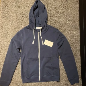 Mörkblå hoodie från Pier One - Säljer en snygg mörkblå hoodie från Pier One. Den har en dragkedja framtill och justerbara vita snören i huvan. Tröja är helt ny med prislapp