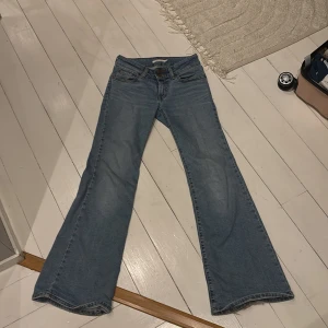 Blå Superlow Flare Jeans - Säljer ett par snygga blå Superlow Flare jeans från Levi's. De har en låg midja och en utsvängd stil som ger en retro känsla. Perfekta för dig som gillar en avslappnad look med en touch av 70-tal.