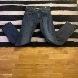 Blå jeans från Lee - Snygga blå jeans från Lee i modellen Daren Zip Fly. De har en klassisk design med dragkedja och knappar. Perfekta för en avslappnad stil. Storlek w30 l32